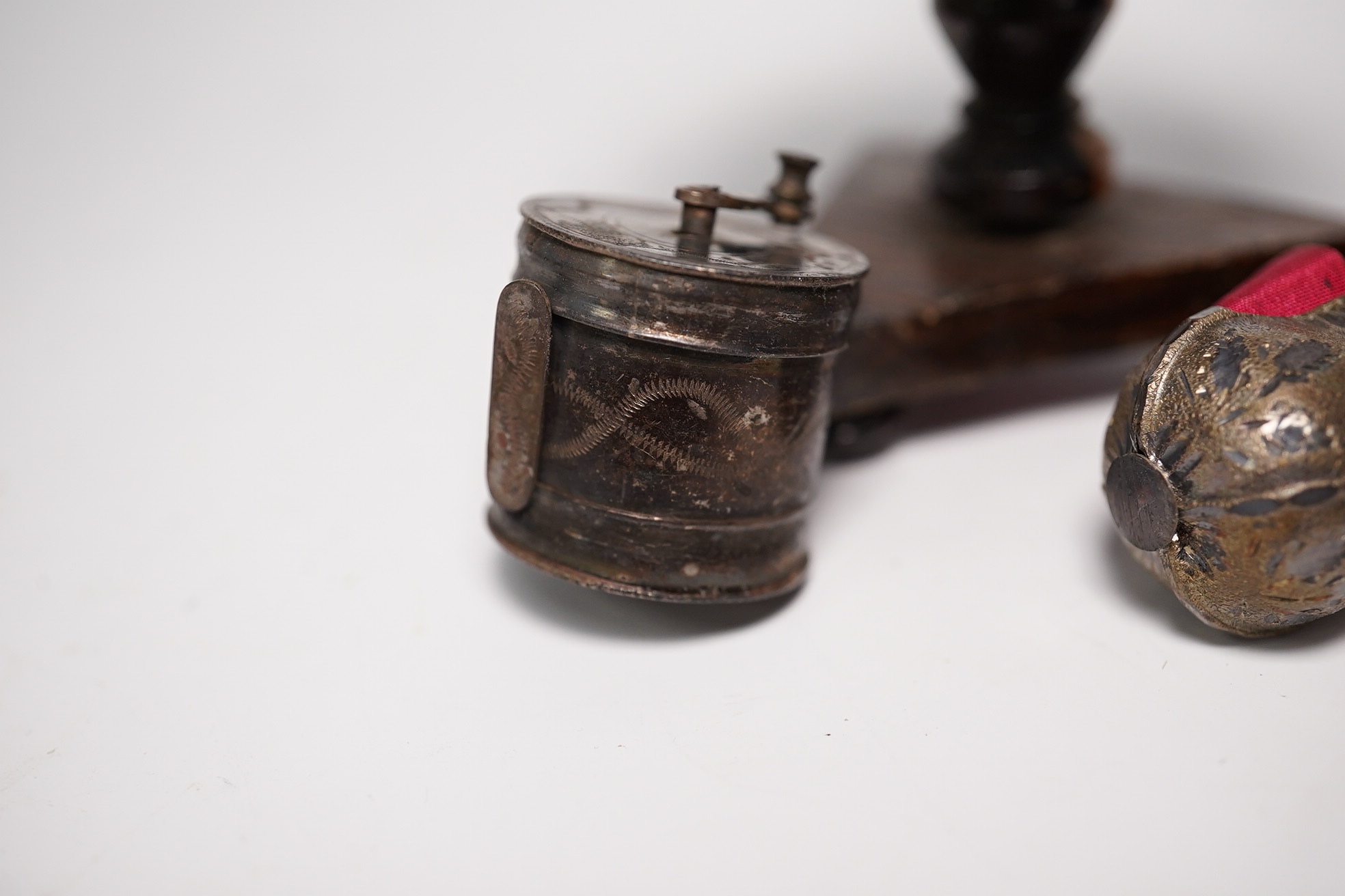 Two early Victorian white metal tape measures and a rosewood miniature 'table' pin cushion. Condition - fair